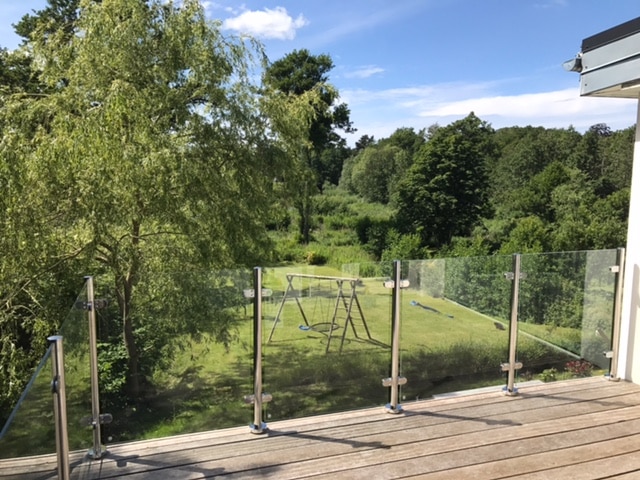 Glasgelænder med rustfrie balustre på hævet træterrasse