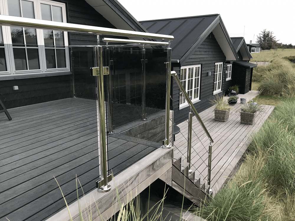 Rustfrit gelænder med glas med 2 lag parasol. Wiregelænder ned ad trappen.